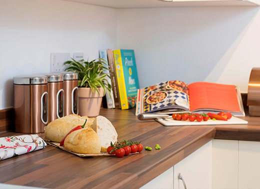 Photo showing a kitchen counter with bread, tomatoes and an open recipe book